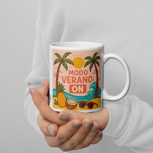 Taza de cerámica blanca con diseño colorido de playa, sol y palmeras, y la frase "Modo Verano: ON", ideal para bebidas calientes como café o té.